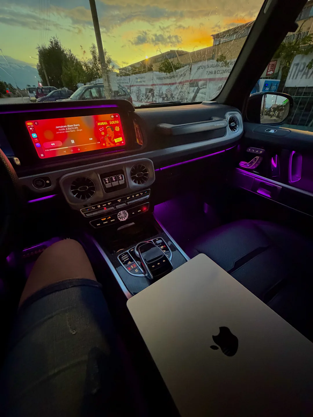 MacBook on the seat of a car lit in purple ambient light
