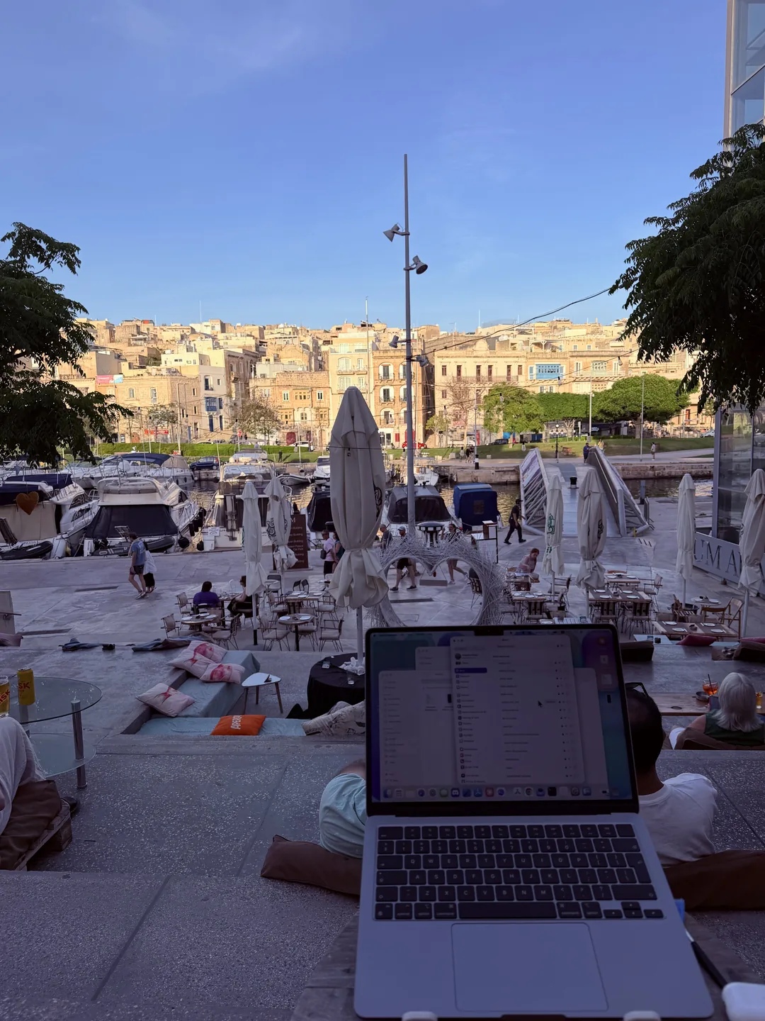 Working on a laptop at a sunny waterfront terrace