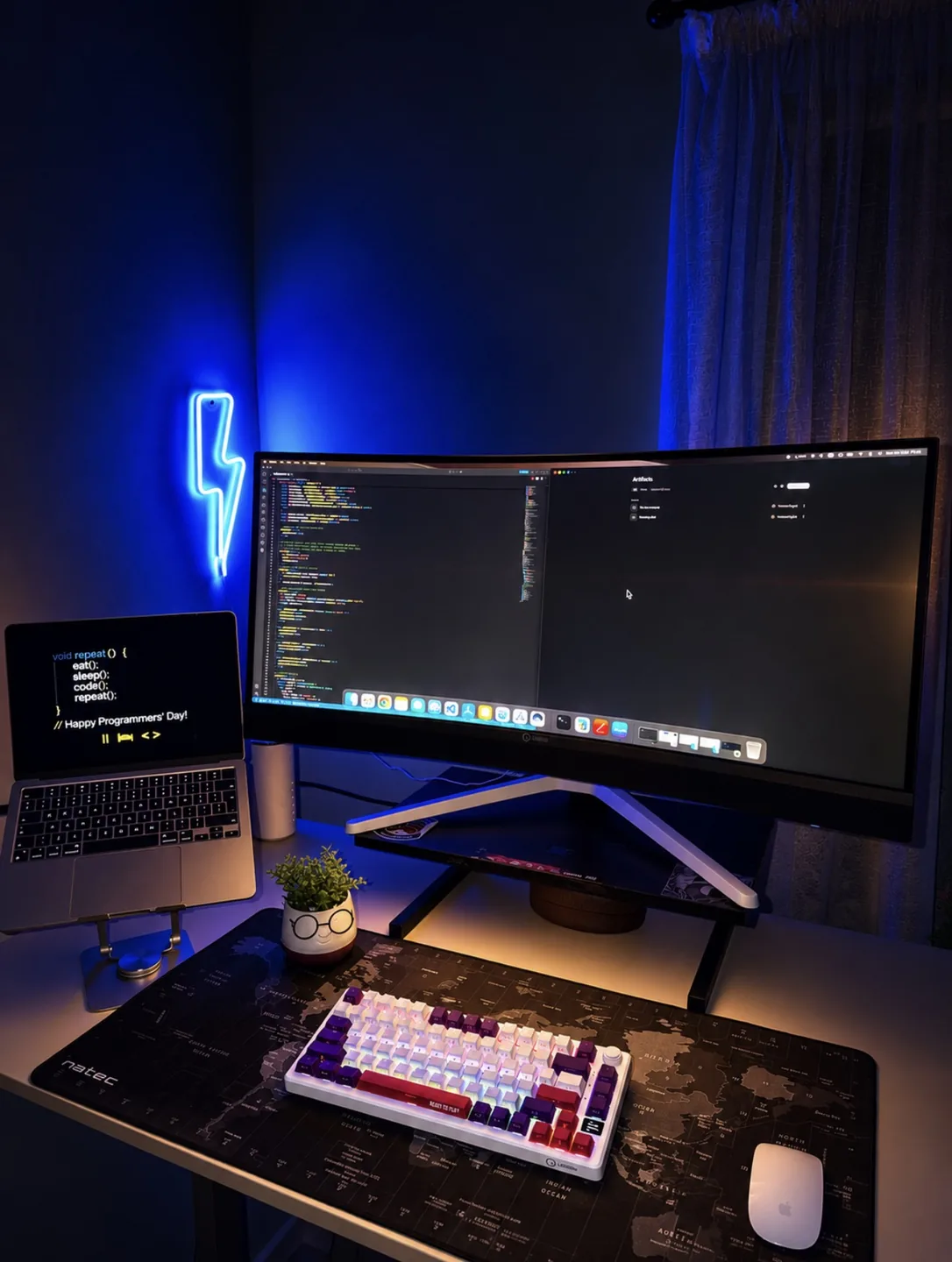 Desk setup with an ultrawide monitor, laptop and a blue neon lightning sign